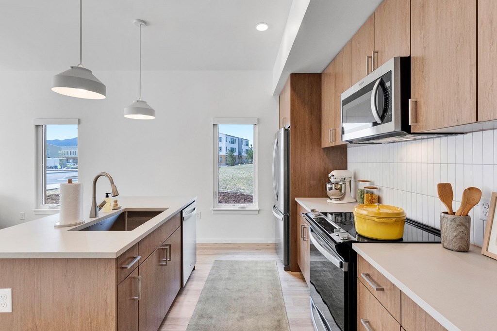 A modern kitchen with wooden cabinets and a black stove top oven.