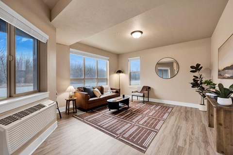 A living room with a brown couch and a round mirror on the wall.