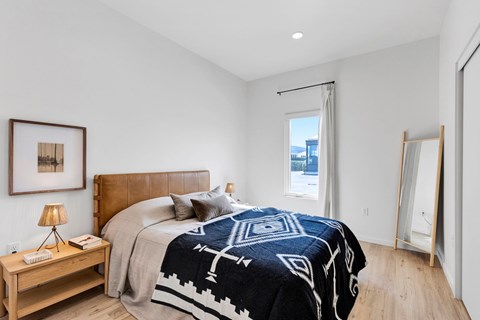 A bedroom with a large bed and a wooden nightstand.