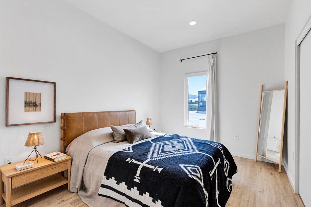 A bedroom with a large bed and a wooden nightstand.