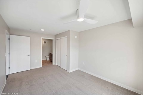 A spacious room with a ceiling fan and carpeted floor.