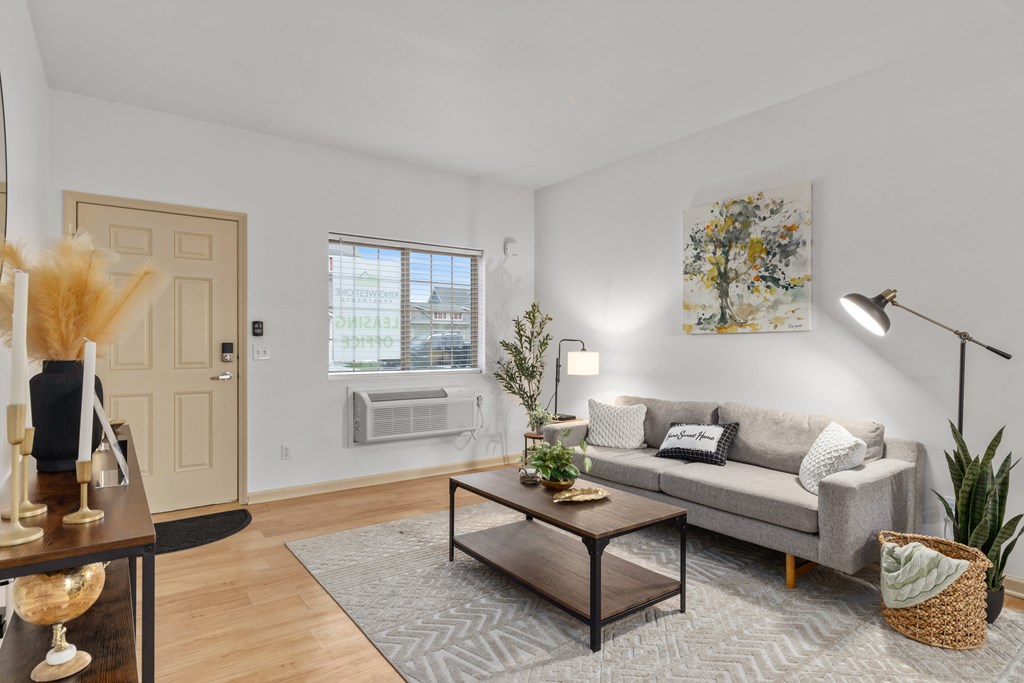 A living room with a grey sofa, a coffee table, and a large window.