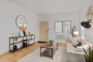 A living room with a white couch, a coffee table, and a round mirror on the wall.