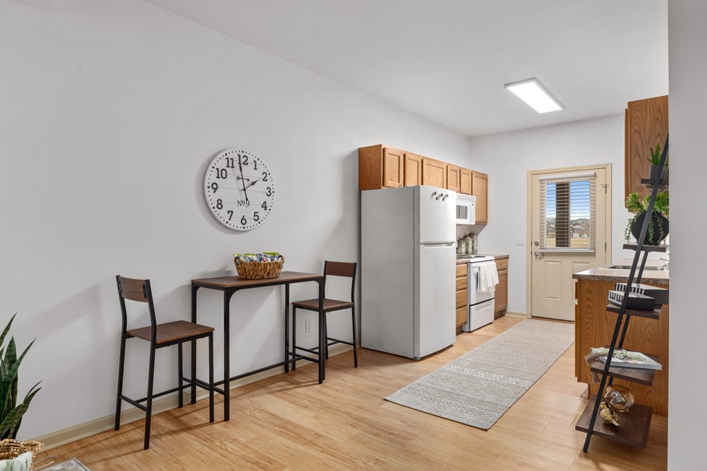 A kitchen with a table and chairs and a clock on the wall.