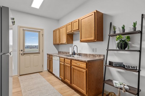 A kitchen with wooden cabinets and a white countertop at King West One Apartments, Billings, MT.
