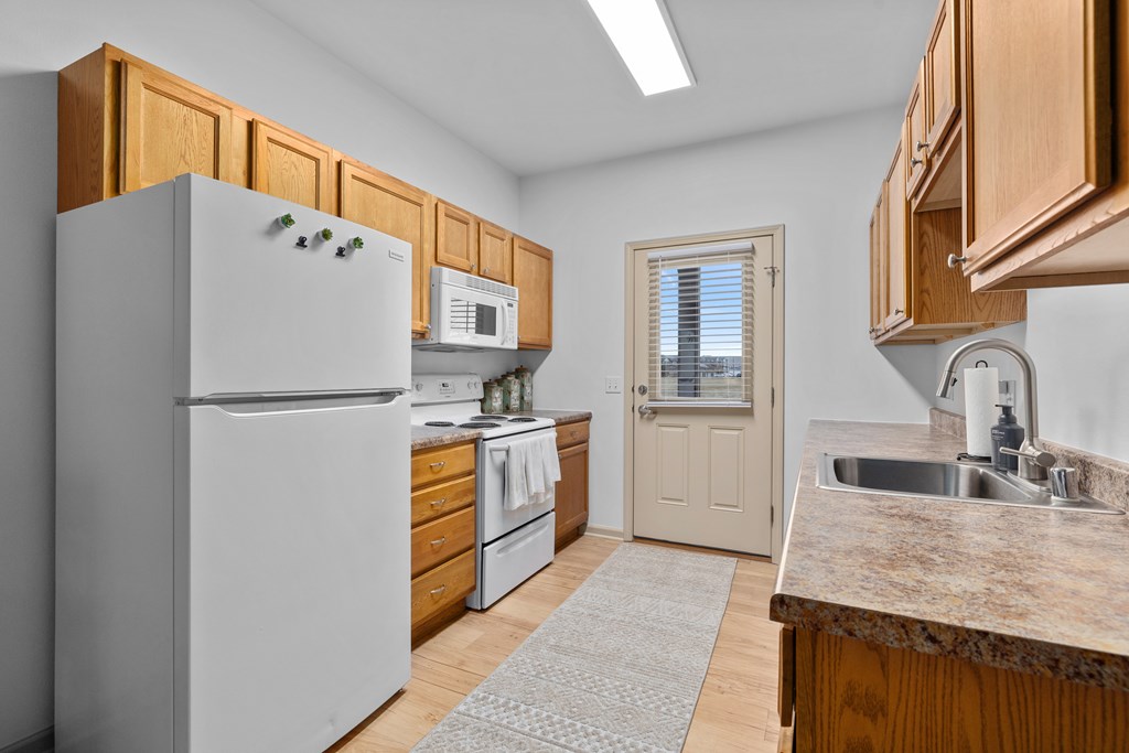 A kitchen with a white refrigerator and wooden cabinets.