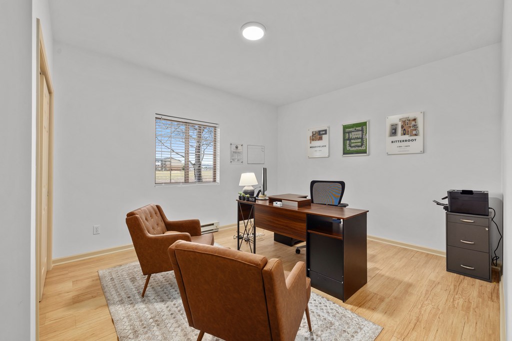 A room with a desk, chairs, and pictures on the wall.