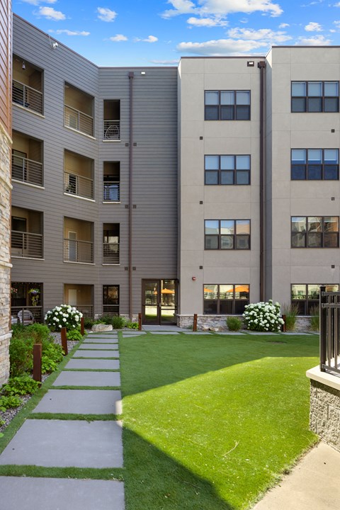an exterior view of an apartment building with a green lawn and sidewalk at Avenue C Apartments, Billings