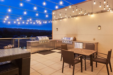 a terrace with tables and chairs and barbecue grill and outdoor lighting at Avenue C Apartments, Montana