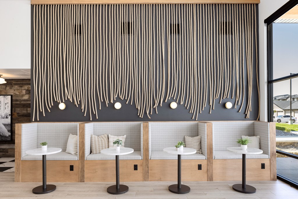 a room with four white tables and four white chairs with pillows on them