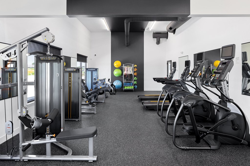 a spacious exercise room with cardio equipment and weights
