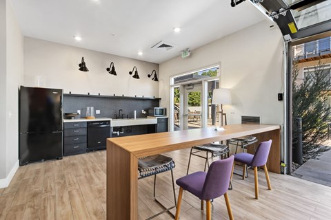 A kitchen with a black fridge and a table with chairs.
