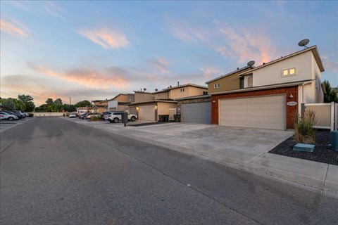 A parking lot with a building and a garage door in the background. at Verraso Village Apartments, Idaho