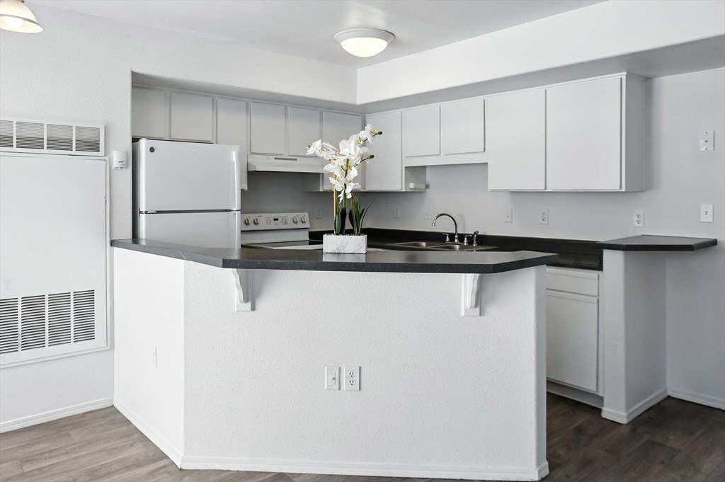 A modern kitchen with white cabinets and a black countertop. at Oakstone Apartments, Clearfield, 84015