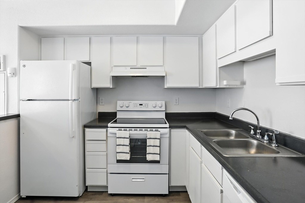 A white kitchen with a stove, sink, and refrigerator. at Oakstone Apartments, Clearfield, Utah