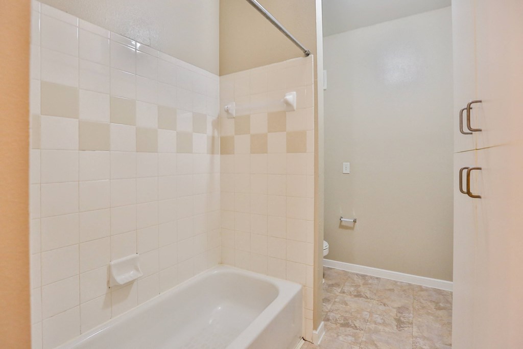 a bathroom with white tile and a white bathtub