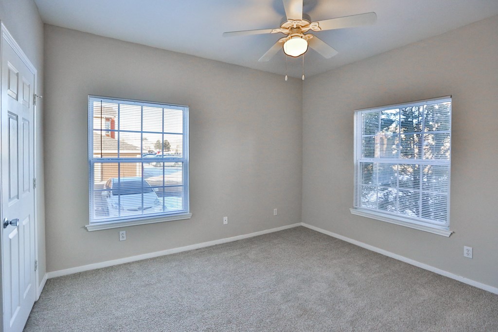 a bedroom with two windows and a ceiling fan