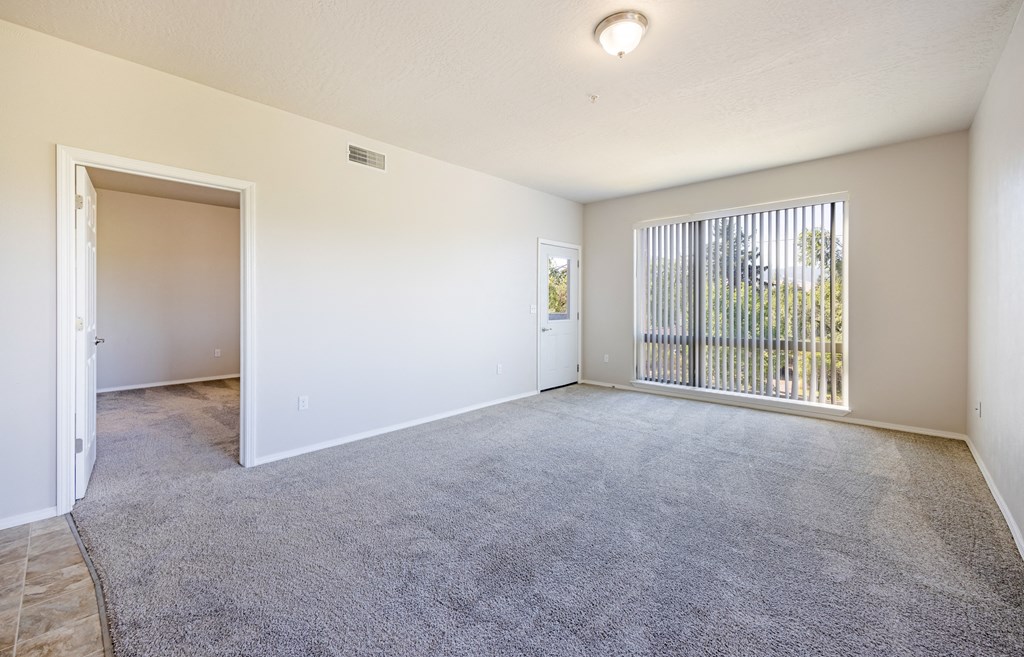 A room with a grey carpet and a window with a view of a fence. at Ashlyn Place, Montana, 59801