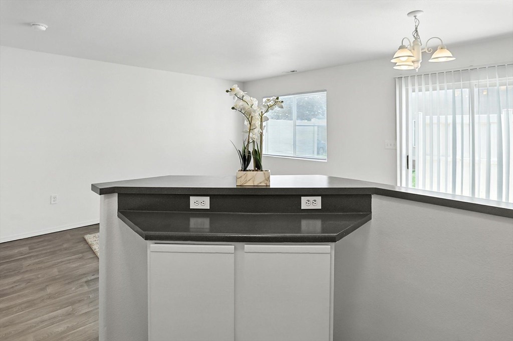 A modern kitchen with a black countertop and a wooden floor. at Oakstone Apartments, Clearfield, Utah