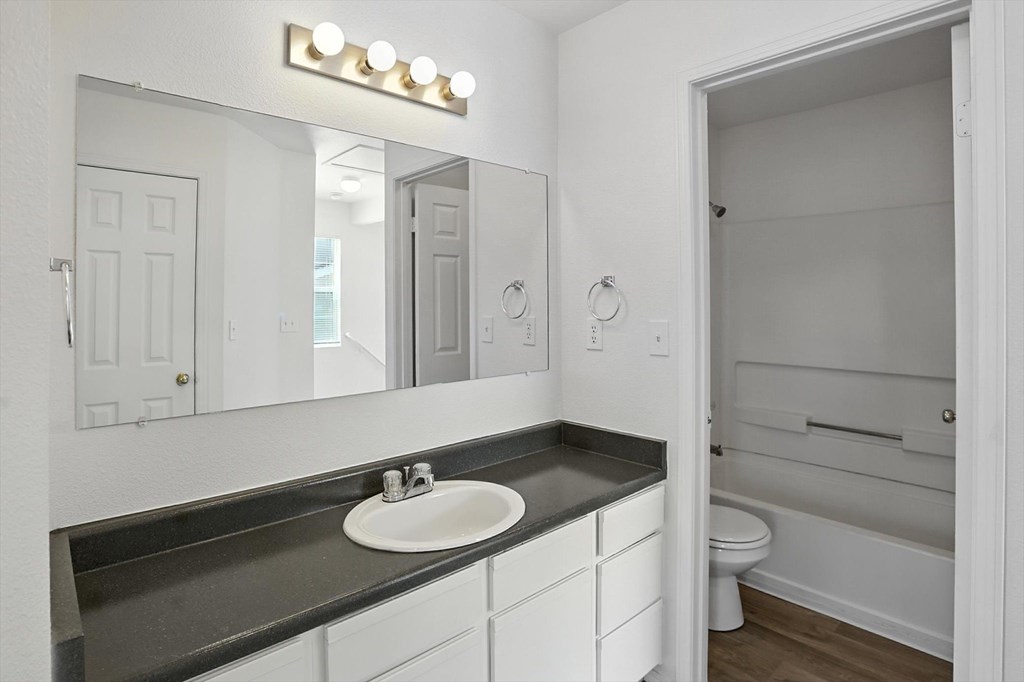 A bathroom with a sink, mirror, and toilet. at Oakstone Apartments, Clearfield, Utah