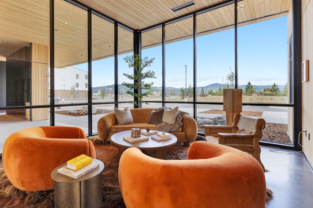 A living room with orange chairs and a round table.
