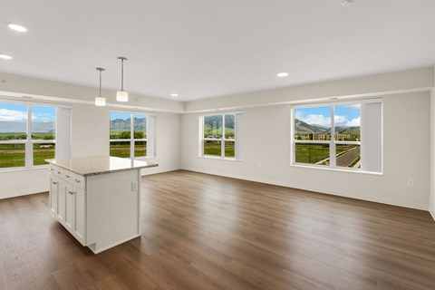 A spacious room with wooden floors and large windows overlooking a green landscape at The Beaumont Apartments, Bozeman, MT