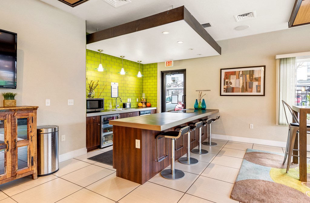a kitchen with a bar with stools and a tv