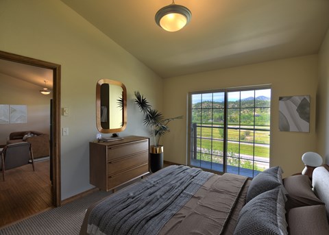 A bedroom with a large bed and a view of the outdoors through the window.