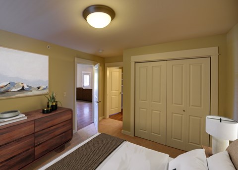 A bedroom with a bed, dresser, and a painting on the wall.