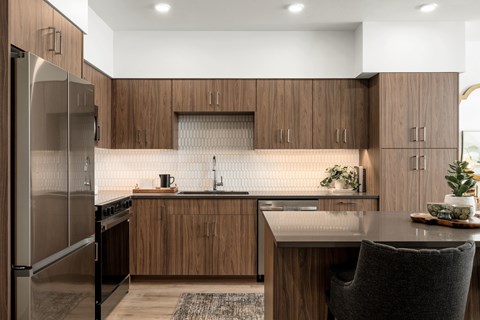 A modern kitchen with wooden cabinets and a stainless steel refrigerator.