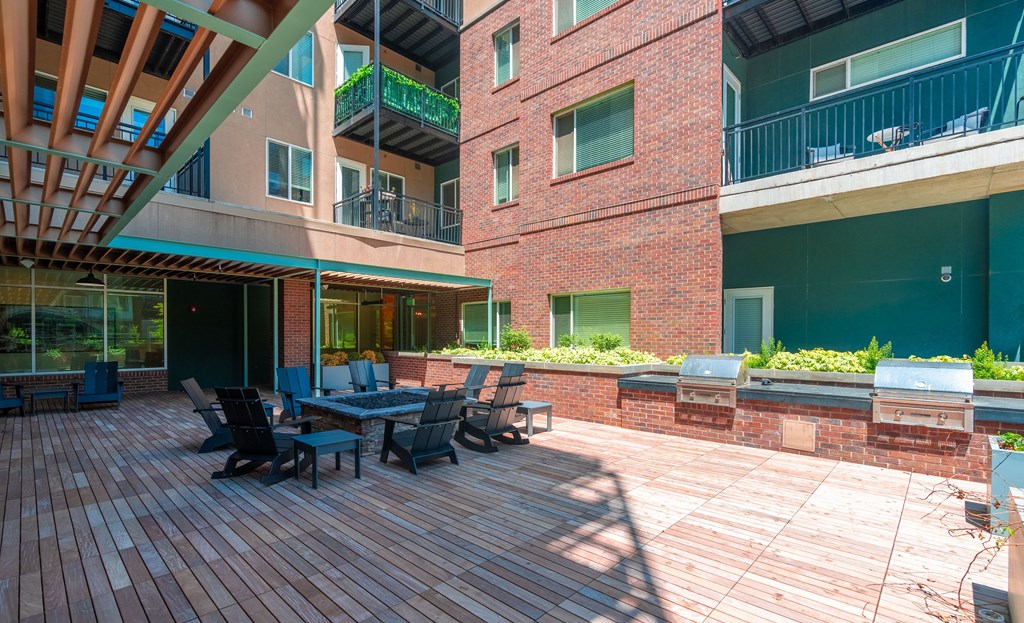 View of the resident fire pit lounge and patio area with bbq grills and red brick walls at Sylvan Uptown,Colorado, Denver