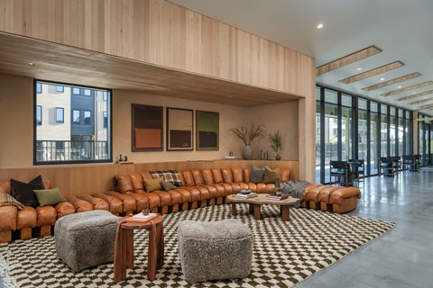A living room with a large orange sofa and a checkered rug.