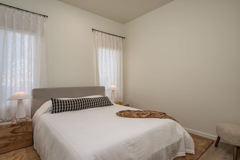 A bedroom with a large bed and a chair.