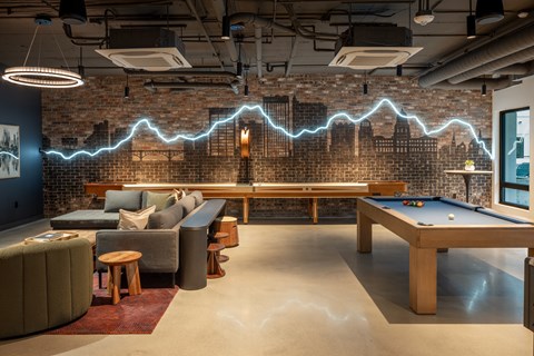 A room with a pool table and a brick wall with a lightning bolt design.
