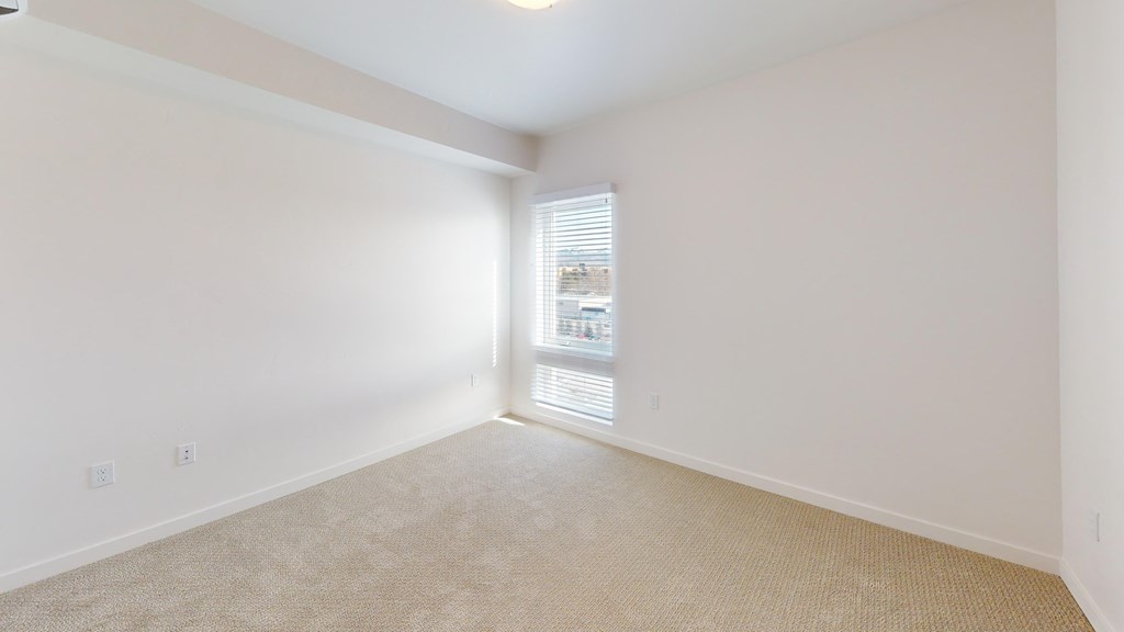an empty room with a window and white walls