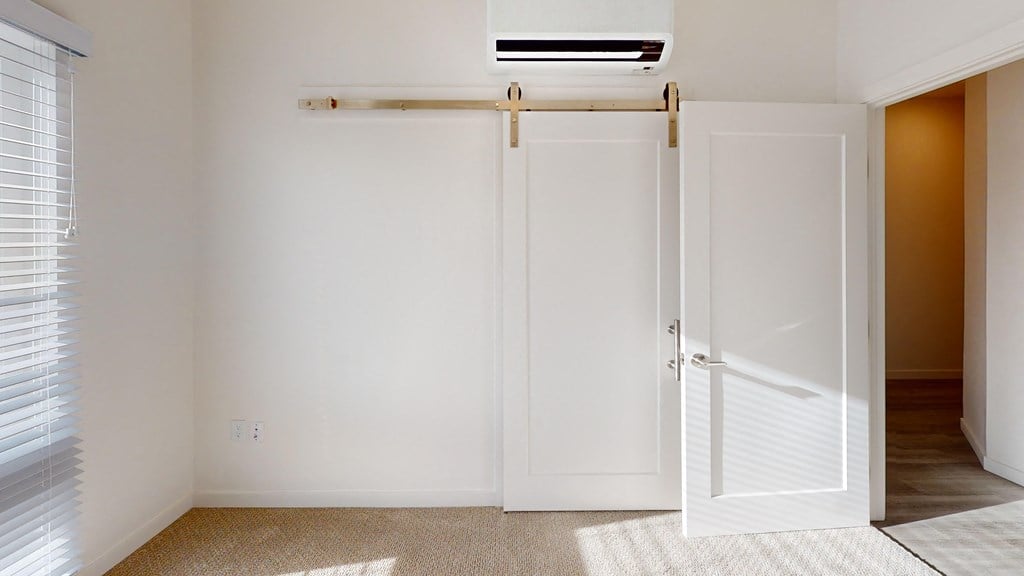 an empty room with two closet doors and a window