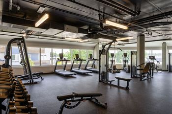 a gym with treadmills and other exercise equipment in a building with windows