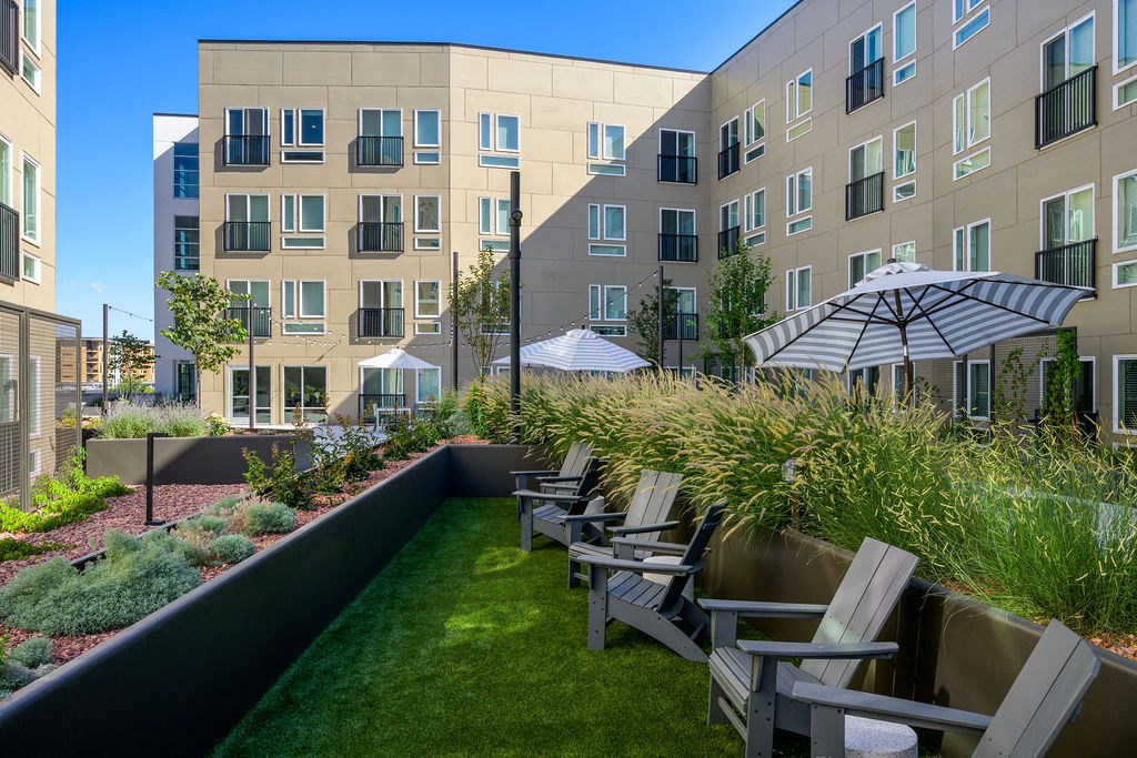 a patio with chairs and an umbrella in front of an apartment building at Crosshatch, Idaho, 83714