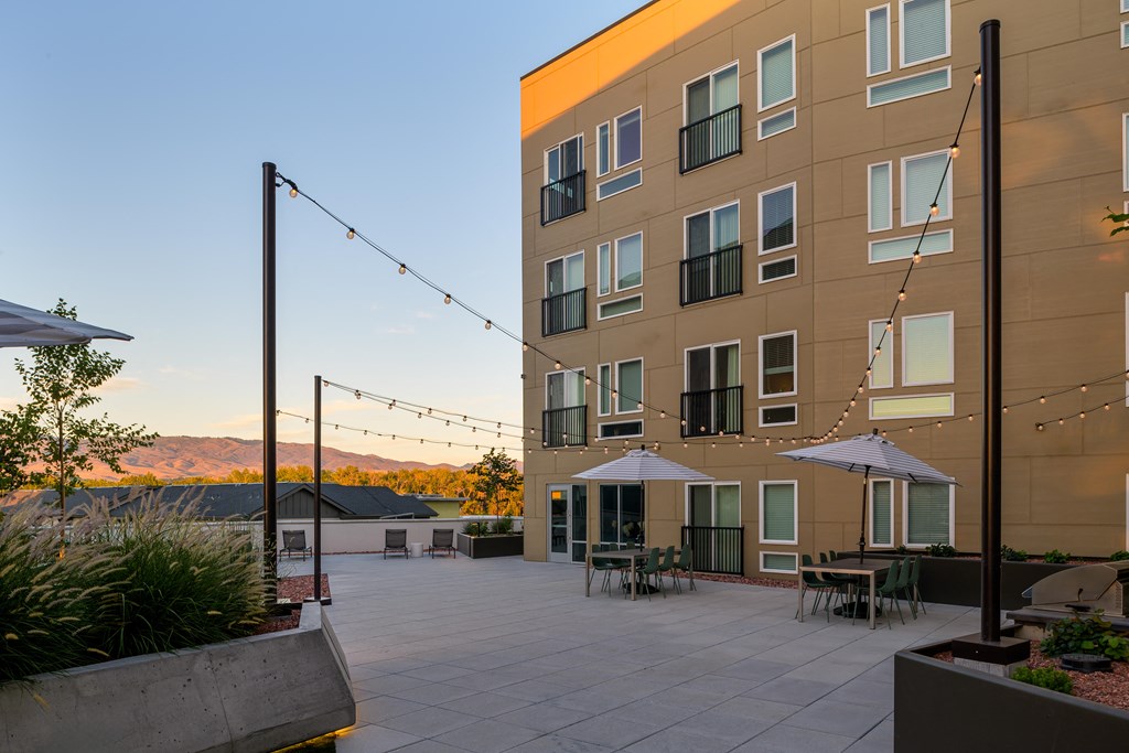 an outdoor patio with tables and umbrellas in front of a building at Crosshatch, Garden City, 83714