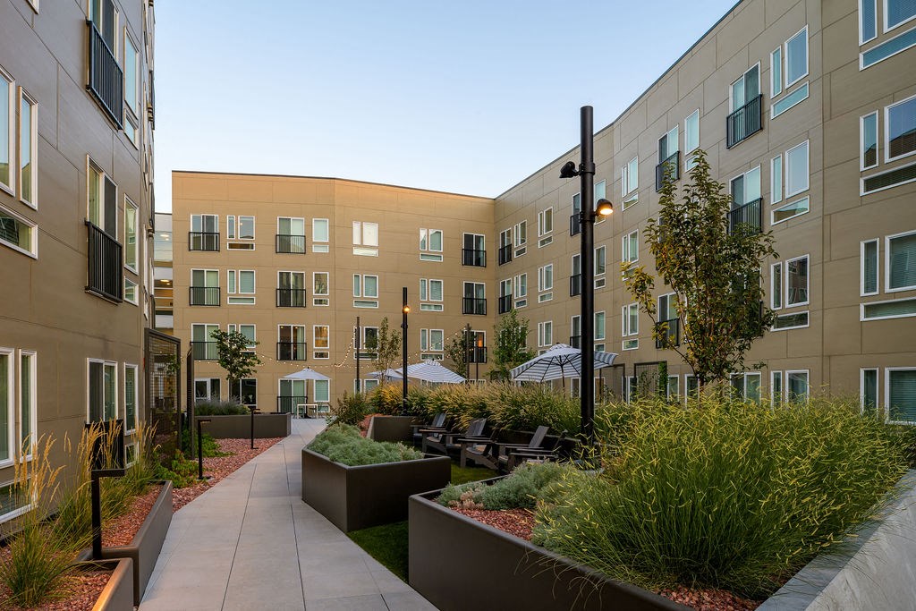 a courtyard with benches and plants in front of an apartment building at Crosshatch, Garden City, Idaho