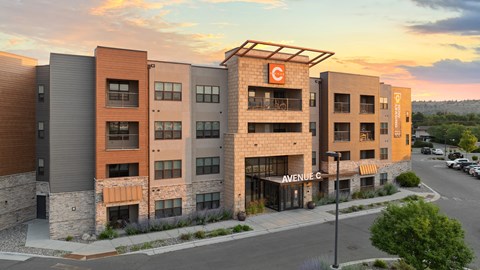 a large apartment building with a sunset in the background at Avenue C Apartments, Billings, MT, 59102