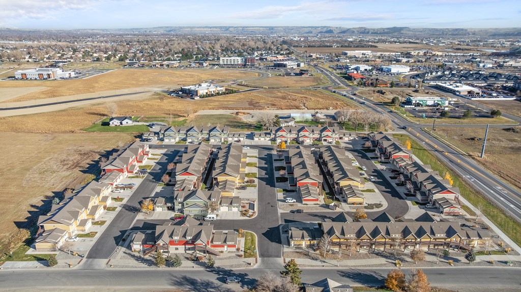 A large, open parking lot is surrounded by a mix of residential and commercial buildings.