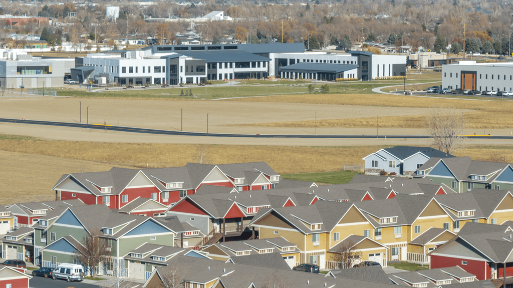 A suburban neighborhood with houses and a large building in the background.