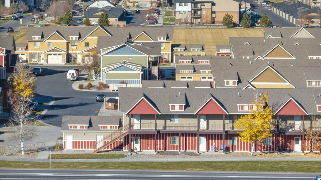 A large building with a red roof is surrounded by smaller houses.
