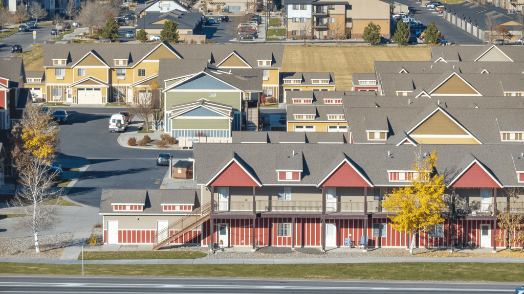 A large building with a red roof is surrounded by smaller buildings.