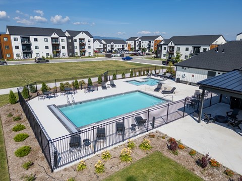 A swimming pool surrounded by a black fence with a grassy area at Silverbrook Apartments, Kalispell
