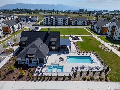 A large house with a pool in the foreground and several smaller houses in the background. at Silverbrook Apartments, Kalispell, MT, 59901