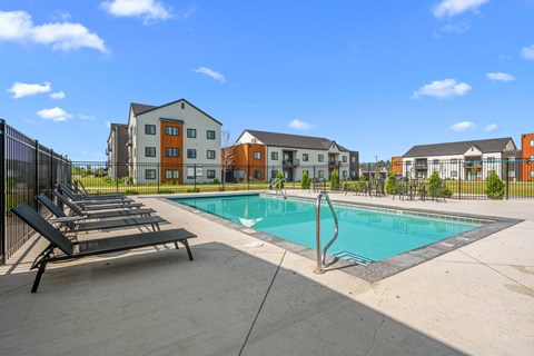 A swimming pool surrounded by lounge chairs and view of apartment buildings at Silverbrook Apartments, Kalispell