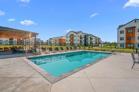 A swimming pool surrounded by lounge chairs and view of outdoor lounge area and apartment buildings at Silverbrook Apartments, Kalispell