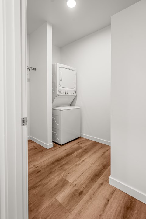 A white washing machine is in a small room with wooden floors at Silverbrook Apartments, MT 59901